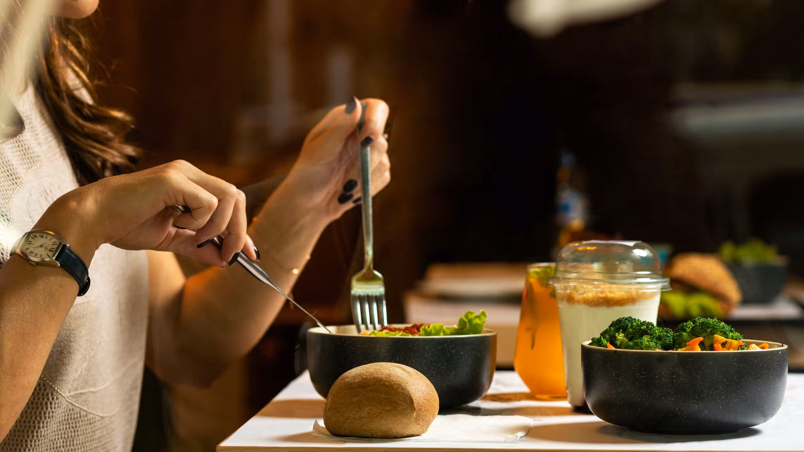 women eating a bowl of vegetables with fork and knife